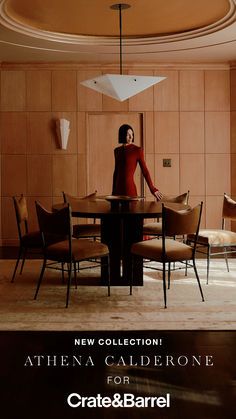 a woman standing at a round table in a room with chairs and lamps on the ceiling