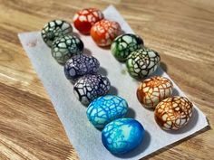 seven different colored marbles sitting on top of a piece of paper next to each other