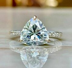 a close up of a diamond ring on a surface with water reflection in the foreground