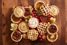 many pies and fruit are arranged on a wooden table