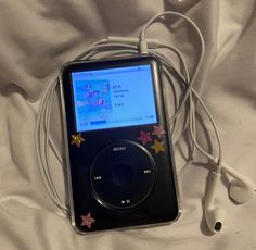 an mp3 player is laying on a bed with ear buds and headphones attached to it