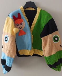 a colorful sweater hanging on a wall with a stuffed animal in the front and back