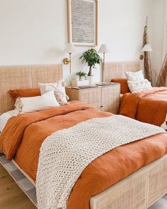 two beds with orange covers and blankets in a room