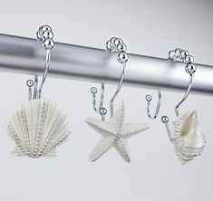 three sea shells hang from a metal rod