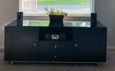 an entertainment center with a potted plant sitting on it in front of a window