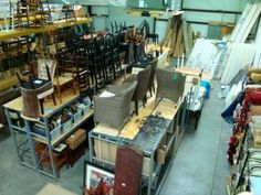 many chairs and tables are stacked up in a warehouse