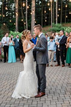 a bride and groom are dancing together in front of an outdoor wedding party full of people