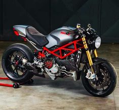 a black and red motorcycle parked on top of a cement floor next to a wall