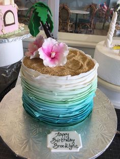 there is a cake that has been decorated with flowers and sand on the bottom layer