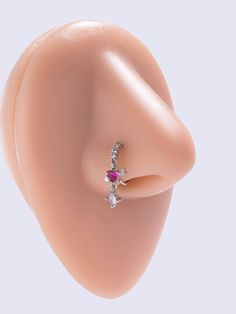 a close up view of an ear with a pink stone and diamond ring on it