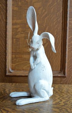 a white rabbit statue sitting on top of a wooden table