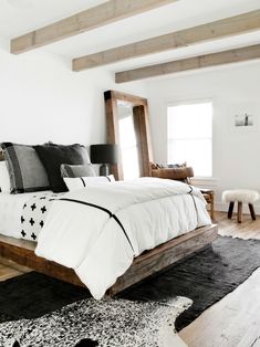 a white bed with black and white comforter in a bedroom next to a window