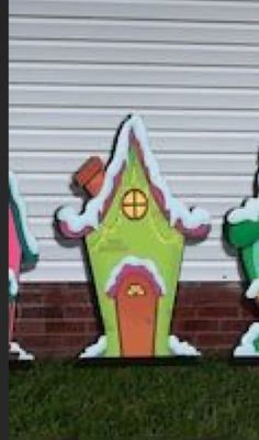 three snowmen are standing in front of a house with a gingerbread house on it