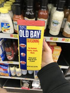 someone is holding up a box of old bay seasoning in front of the shelves