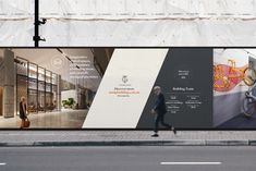 a man walking down the street in front of a building with large billboards on it's side