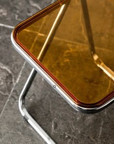 an upside down glass table on a metal stand with marbled flooring and grey tile