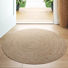 a round rug on the floor in front of an open door with potted plants