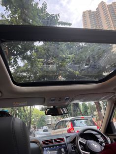 the interior of a car with trees and buildings in the backgroung area