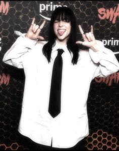 a man with long black hair wearing a white shirt and tie making the peace sign