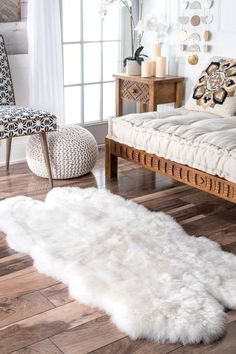 a white sheepskin rug on the floor in front of a couch, chair and ottoman