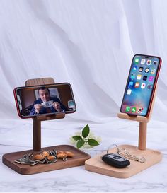 two cell phones are sitting on wooden stands and one is displaying an image of a man