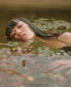 a woman floating in water with leaves on the ground