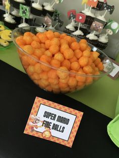 a bowl full of oranges sitting on top of a table next to cupcakes