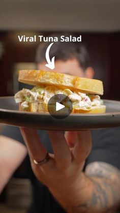 a person holding a plate with a sandwich on it and the words virtual tuna salad