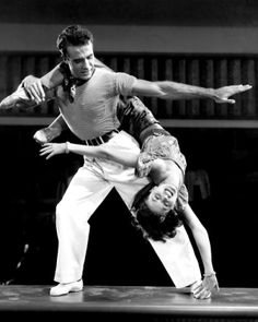 a man and woman are performing an acrobatic dance in black and white