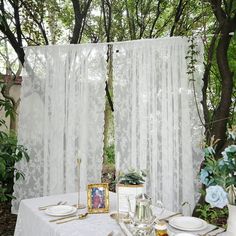 the table is set with plates, silverware and flowers in front of an open window