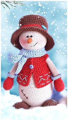 a crocheted snowman is sitting in the snow wearing a hat and scarf