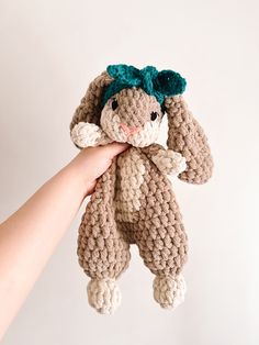 a hand holding a crocheted stuffed animal in the shape of a bunny with green hair