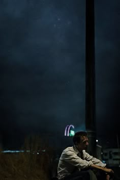 two men sitting on the ground at night with their eyes closed and one looking up