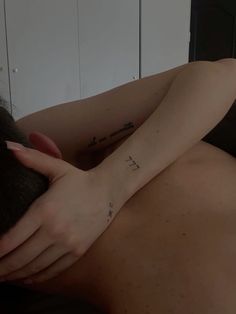 a woman with a small tattoo on her arm laying next to a man's head