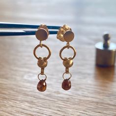 Here we have a delicate pair of handmade 14kt yellow gold and diamond briolette drop earrings.   The diamonds are rich red, translucent fancy cognac 3.5x4mm briolettes, weighing 40pt each (that is 80pt total for the set... almost 1 carat!).  Each briolette is dangling from yellow gold dangle fittings, all set to circular gold studs with butterfly push backs. The total drop length of the earrings is 2cm.  Perfect for everyday wear, or that special occasion.  Different lighting conditions are show Yellow Gold Hypoallergenic Jewelry With Briolette Shape, Modern Yellow Gold Briolette Earrings, Modern Gold Briolette Earrings, Gold Briolette Earrings, Gold Dangle Earrings With Rose Cut Diamonds, Gold Briolette Earrings, Pierced, Gold Dainty Earrings With Rose Cut Diamonds, Dainty Gold Earrings With Rose Cut Diamonds, Gold Briolette Fine Jewelry Earrings