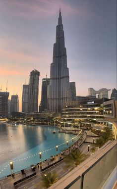 the city skyline is lit up at dusk, with tall buildings in the foreground