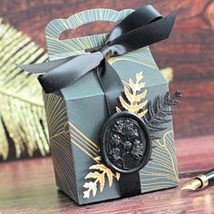 a black and gold gift box with a wax stamp on the front, sitting on a wooden table