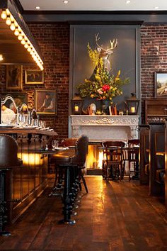 a dimly lit room with bar stools and an antelope painting on the wall