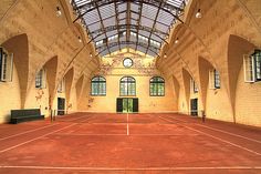 an indoor tennis court with benches and windows