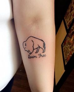 a woman's arm with a small buffalo tattoo on it that says roam free