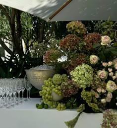 a table topped with lots of flowers and wine glasses next to each other on top of a white table