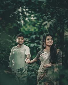 a man and woman standing next to each other in the woods