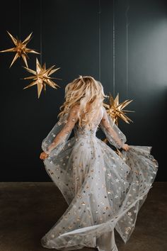 a woman in a white dress and gold stars hanging from the ceiling