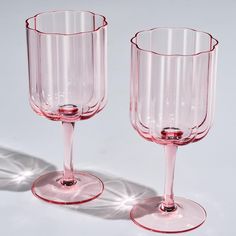 two pink wine glasses sitting next to each other