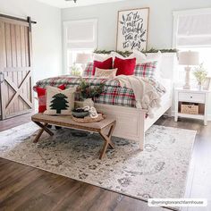 a bedroom decorated for christmas with plaid bedding and red pillows, pine tree on bench