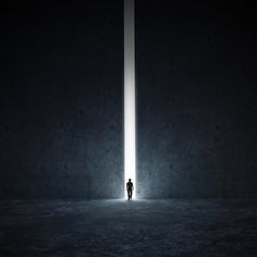 a person standing in the middle of a dark room with a light at the end