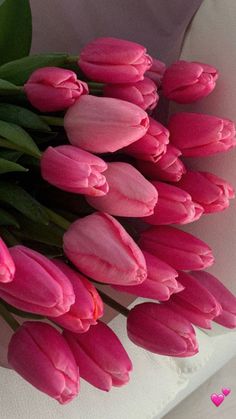 a bunch of pink tulips sitting on top of a white tablecloth with hearts