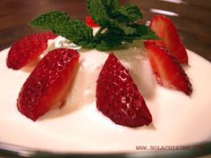 some strawberries are sitting on top of yogurt in a glass bowl with mint sprig