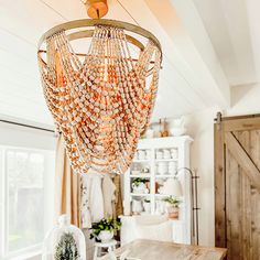 a chandelier hanging over a wooden table in a room with white walls and wood floors