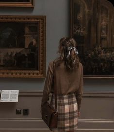 a woman standing in front of a painting and looking at the paintings on the wall